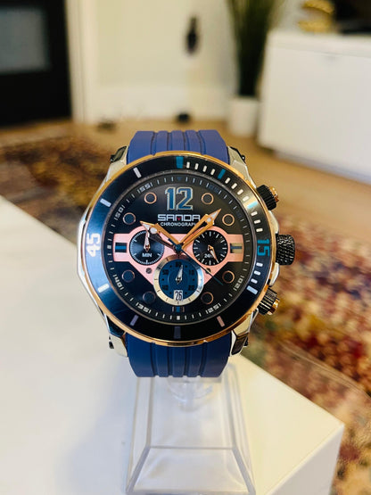 Sanda watch with blue strap on a stand in a blurred indoor setting